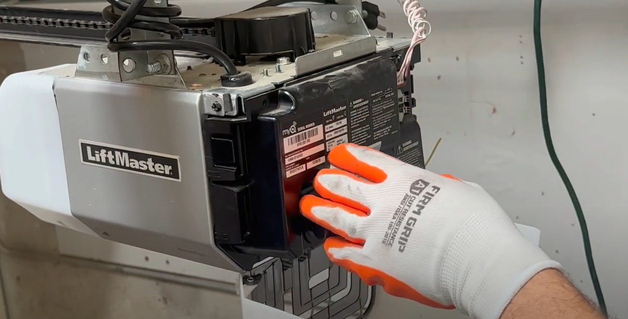 A professional technician repairing a garage door opener in Sarasota, Florida, using branded tools and equipment for local garage door opener repair services.