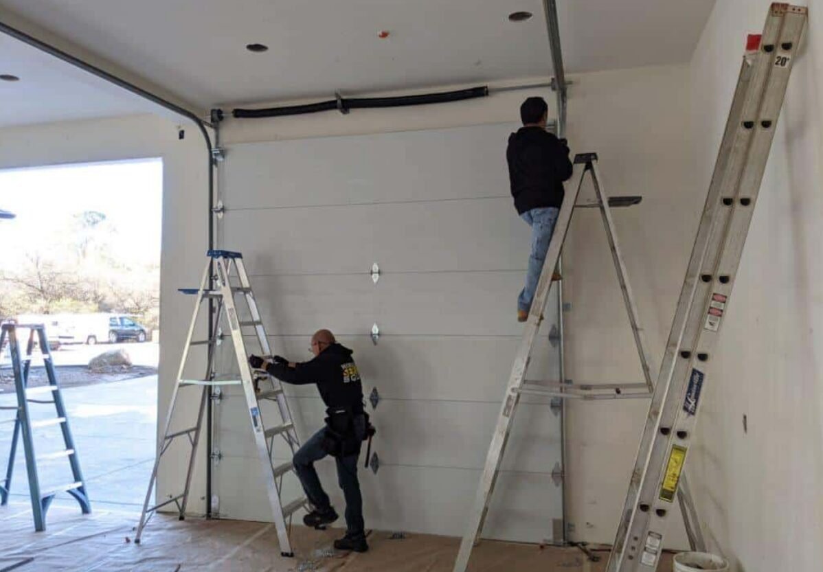 Technician repairing a commercial garage door in Sarasota, FL, showcasing professional tools and expertise in local garage door repair services."