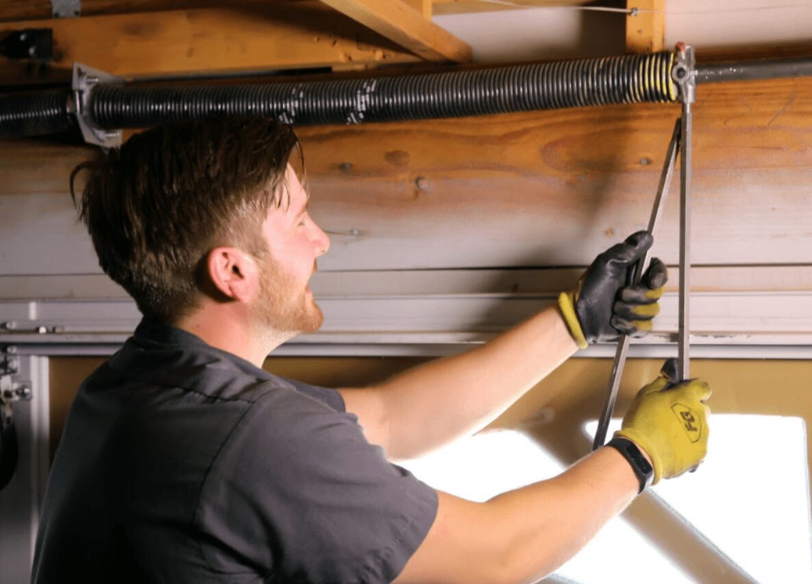 Technician fixing a garage door spring with tools, providing professional garage door spring repair services in Sarasota, FL.